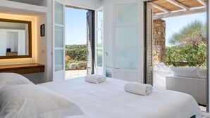 A bedroom with a large bed, a wooden ceiling, and a view of the outdoors. - Infinity View and SUNSET Over Aegean Sea, PRIVCY & Security (Mykonos)