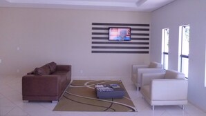 Una sala de estar moderna con un sofá marrón, un sofá blanco y una mesita de centro. Hay un televisor de pantalla plana montado en la pared.