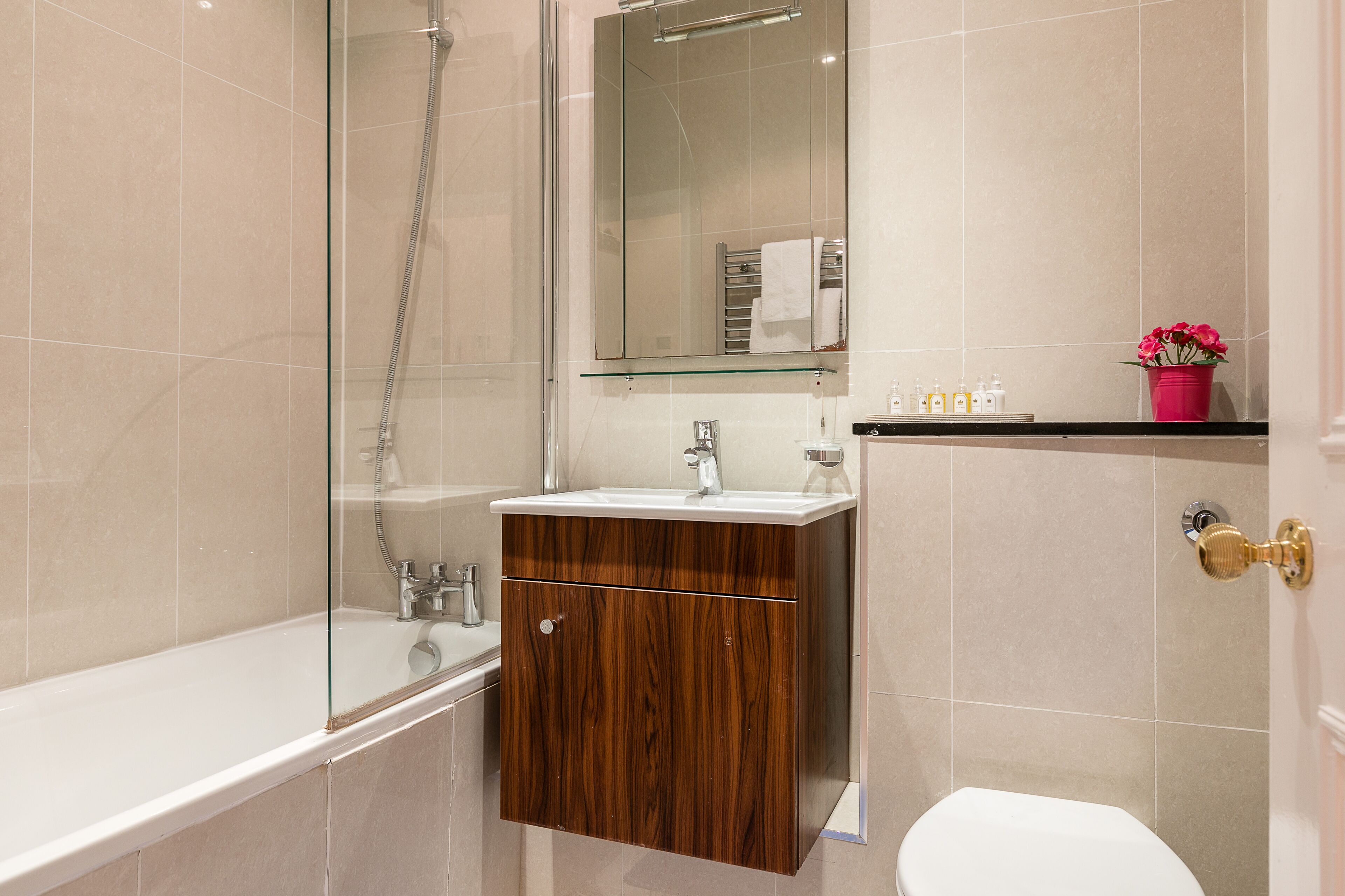 A modern bathroom with a glass-enclosed shower, a wooden vanity with a sink, and a toilet.