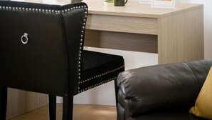 A room with a wooden desk, a black leather chair, a clock on the wall, and a vase with flowers. - 3-bedroom Apartment Lancaster Gate (London)