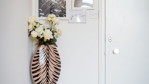 Eine Wand mit gerahmten Bildern, einer Blumenvase und einer Tür.