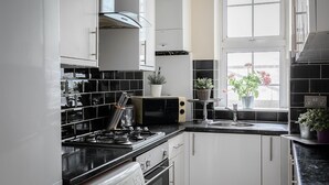 Een moderne keuken met witte kasten, een zwart aanrecht en een raam met plantenpotten.