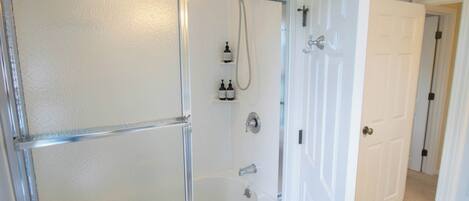 Un baño con cabina de ducha de vidrio, inodoro y lavamanos.