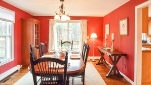A dining room with a wooden table, chairs, and a chandelier. - Beautiful Spacious Family Retreat w/ Pool! (Eastham)