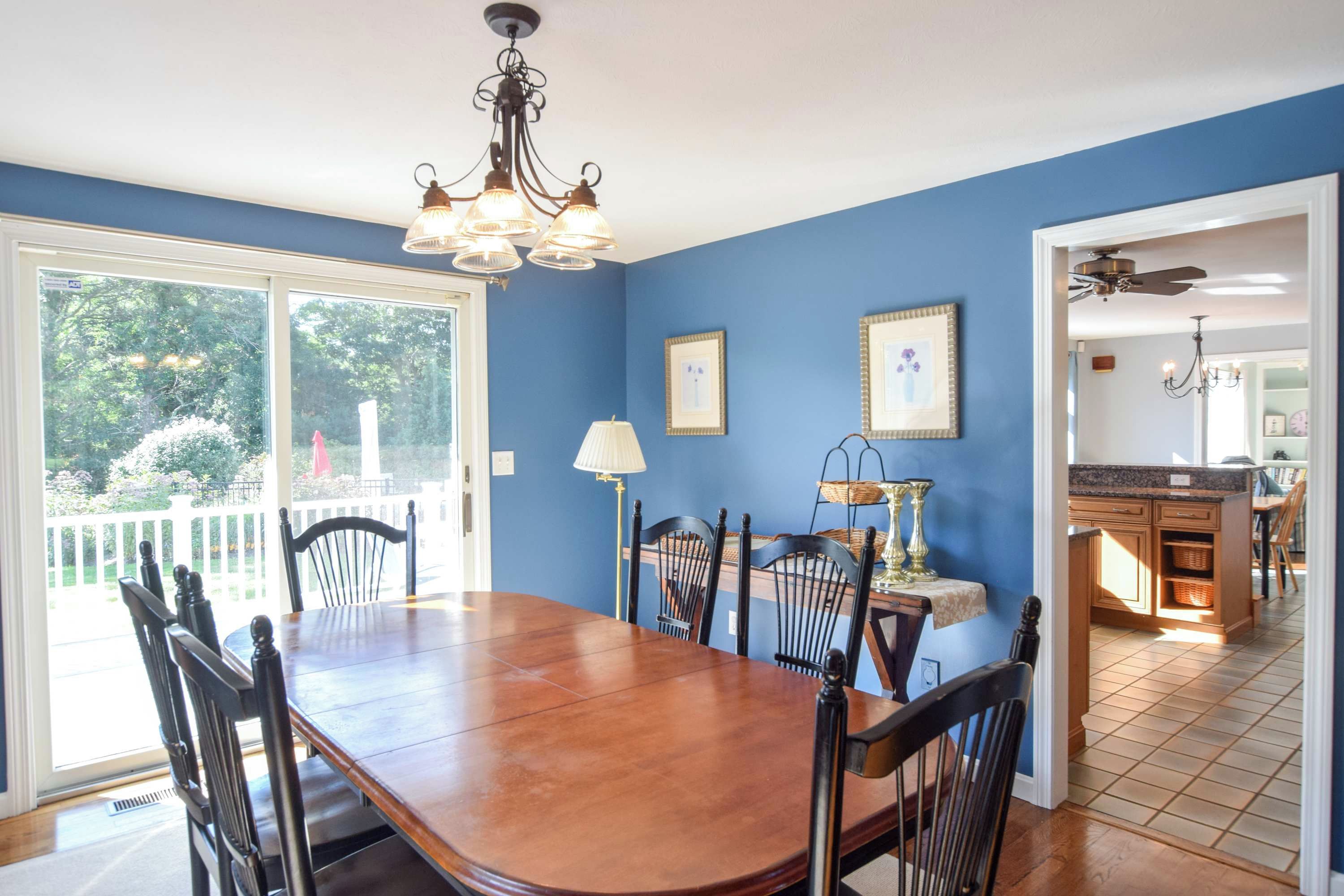 A dining area with a wooden table and chairs, a chandelier, and a view of the outdoors through a sliding glass door.