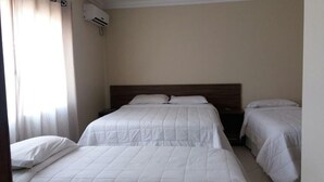 A hotel room with two beds, a wooden headboard, and an air conditioning unit on the wall. - Hotel Imbau Palace (Imbau)