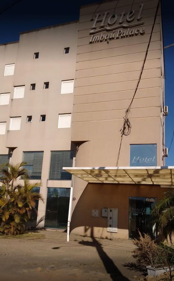 A hotel named "Hotel Imbuc Palace" with a modern facade, multiple windows, and a covered entrance area.