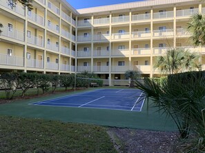 Ein mehrstöckiges Hotel mit Tennisplatz im Innenhof.