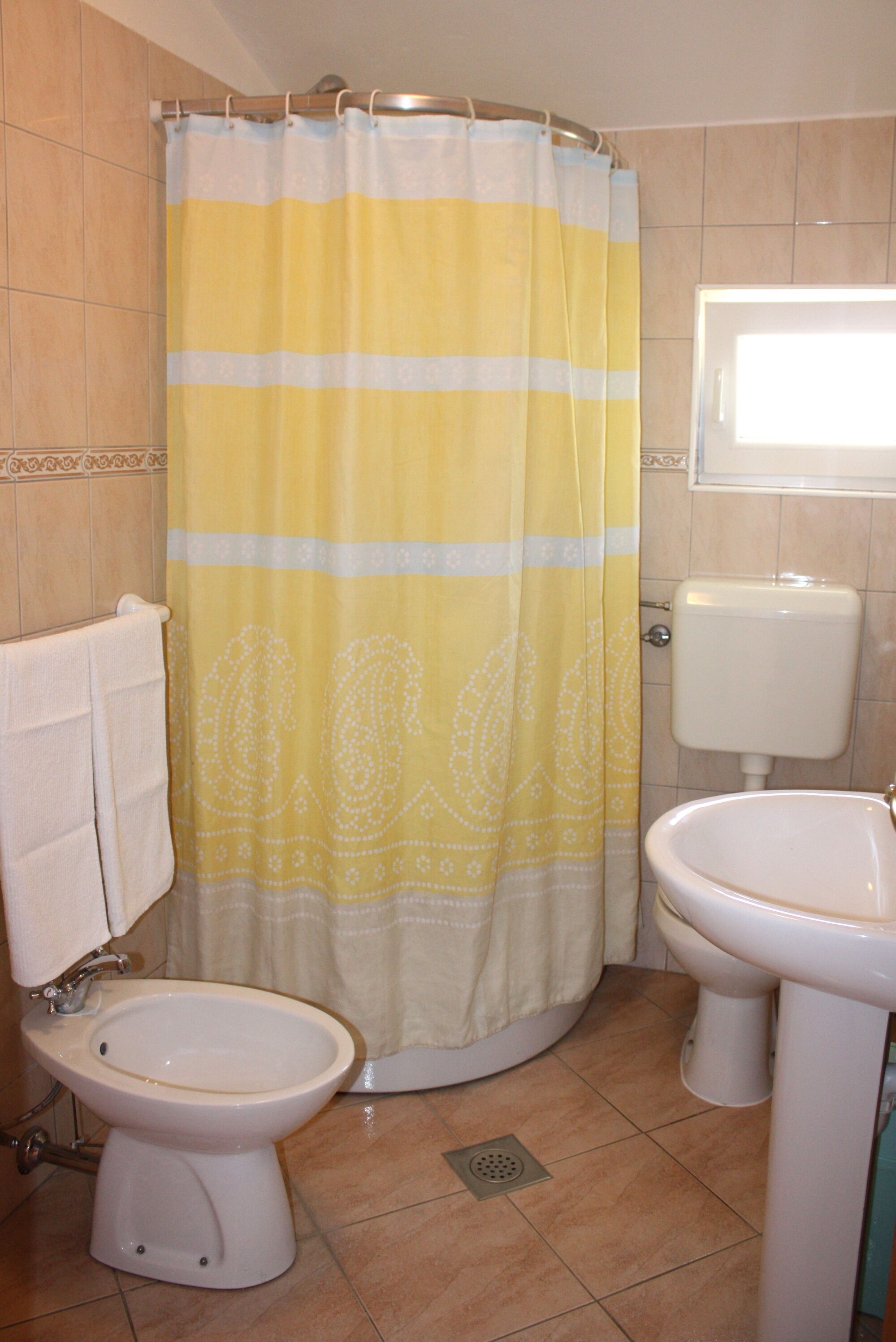 A bathroom with a yellow and white striped shower curtain, a white toilet, and a white sink.