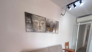 Une pièce moderne avec un canapé en bois, une œuvre d’art accrochée au mur et un couloir menant à une porte.