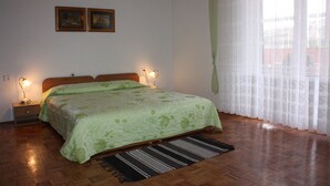 Ein Schlafzimmer mit einem hölzernen Bett, zwei Nachttischlampen, einer grünen Bettdecke und einem gemusterten Teppich.
