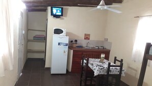 A compact kitchen with a refrigerator, microwave, and a small dining table with chairs. - Descanso puntano (Carpintería)