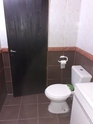A small bathroom with a toilet, a sink, and a door. - Descanso puntano (Carpintería)