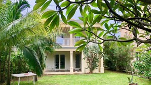 Una casa con patio coperto, prato e vegetazione circostante.