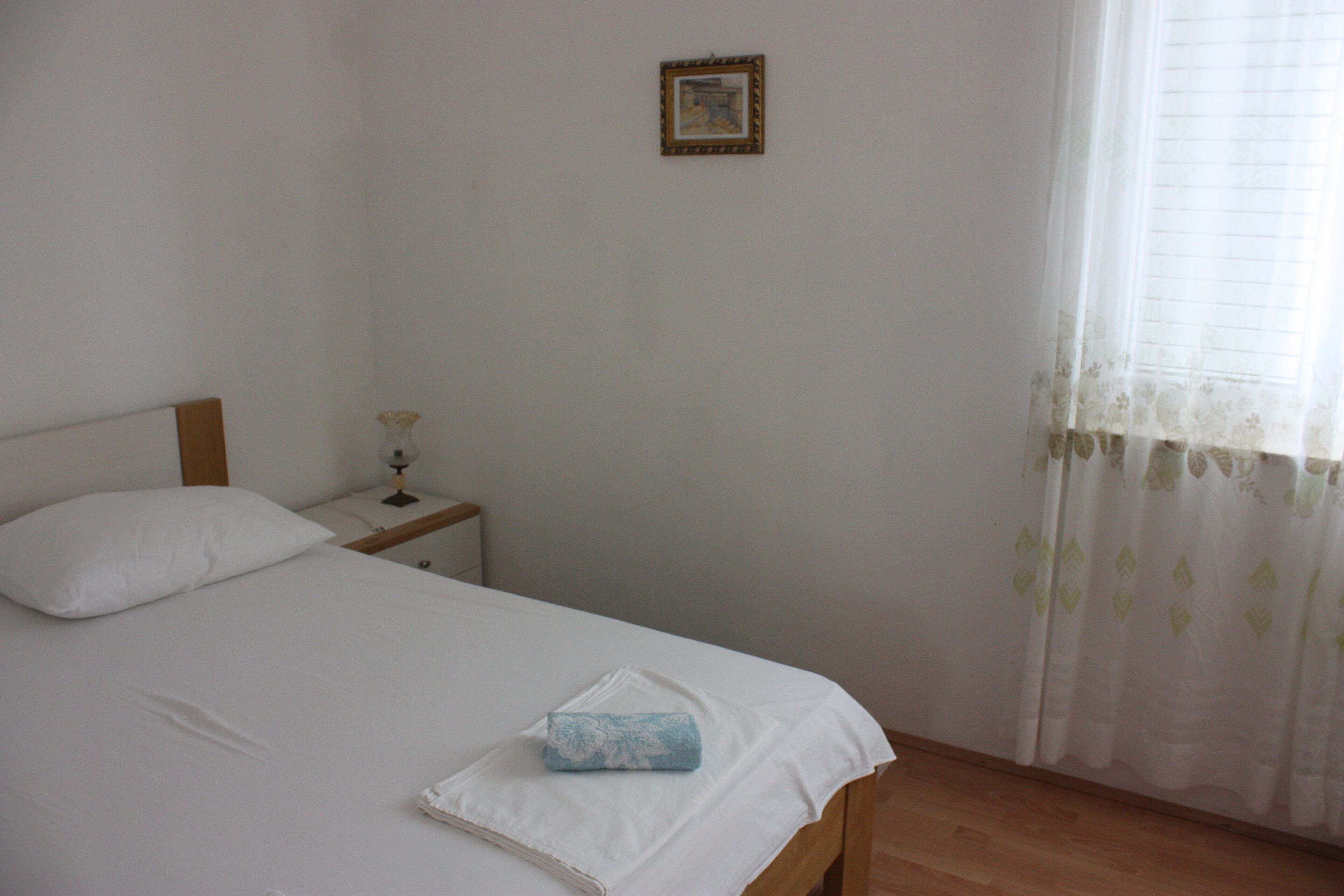 A bedroom with a bed, a nightstand, a lamp, and a window with curtains.