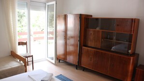A room with a bed, a wooden cabinet, and a chair near a sliding glass door. - Pintar Apartment (Pag)