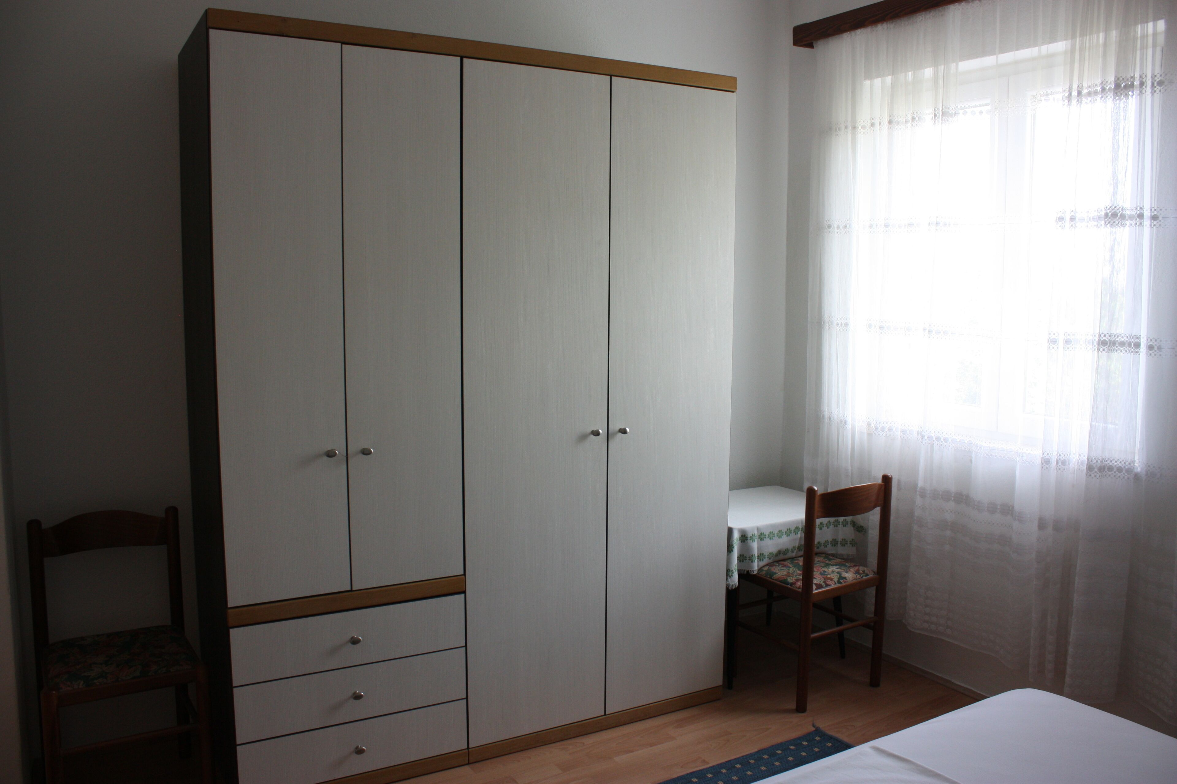 Une chambre avec une armoire, une chaise et une petite table.