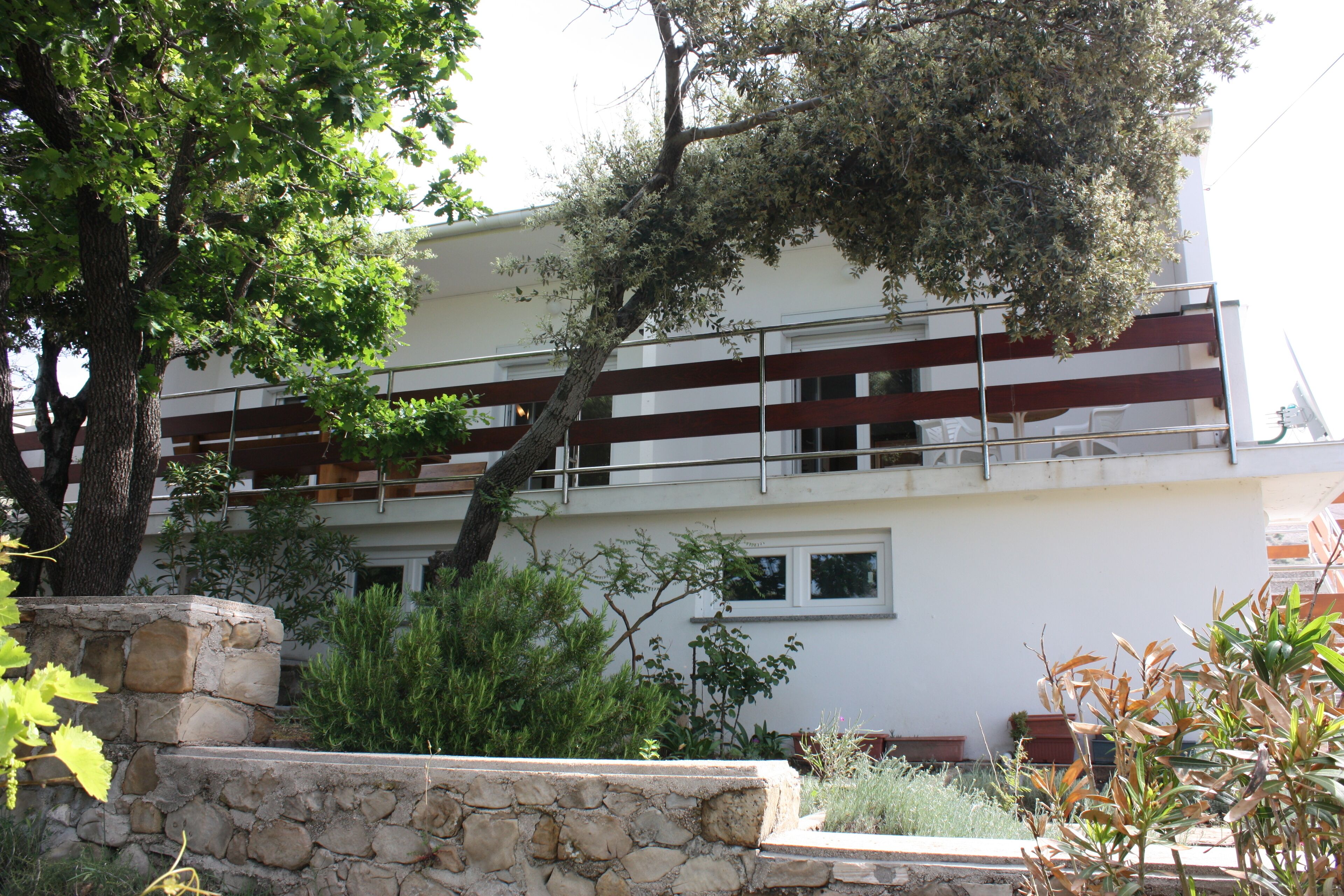 A two-story building with a stone retaining wall and a balcony.