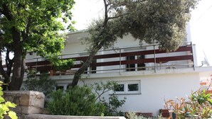 A two-story building with a stone retaining wall and a balcony. - Pintar Apartment (Pag)