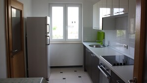 A compact kitchen with a refrigerator, sink, and cabinets. - Pintar Apartment (Pag)