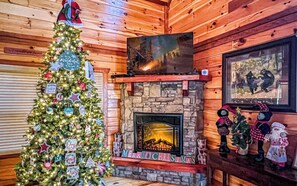 Cozy space with a traditional fireplace, Christmas tree, and artwork, creating a warm and inviting atmosphere.