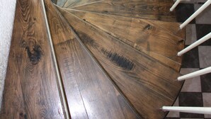 A spiral staircase with wooden steps and white metal railings.