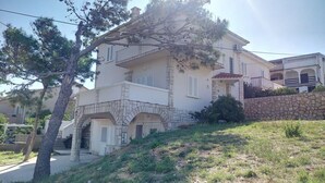 A two-story house with a stone facade, a stone wall, and a small garden area.