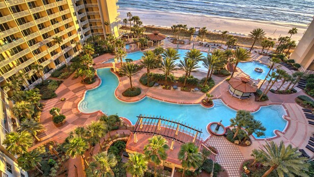 A hotel with a large outdoor swimming pool surrounded by palm trees and a beach view. - Beautiful Beachfront 11th Floor Condo w/ Direct Gulf Views Panama City Beach, FL (Shores of Panama, Panama City Beach)