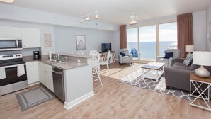 A modern kitchen with a central island, dining area with chairs, a sofa, and a view of the ocean. - Beautiful Beachfront 11th Floor Condo w/ Direct Gulf Views Panama City Beach, FL (Shores of Panama, Panama City Beach)