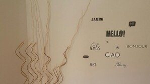 A wall with a decorative arrangement of wavy lines and a small wooden table with a vase and seashells. - Wish Apartment (Pag)
