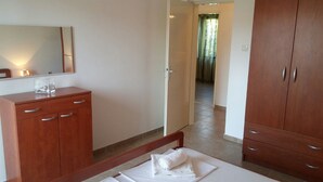 A hotel room with a wooden wardrobe, a bed with a white pillow, and a mirror on the wall. - Wish Apartment (Pag)