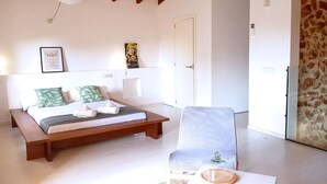 A bedroom with a bed, a chair, a door, and a wall with a poster. - Spectacular country house, centenary, with pool in Sencelles. (Cas Canar)