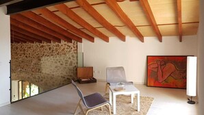 A modern interior with a stone wall, wooden ceiling beams, a painting, and a chair. - Spectacular country house, centenary, with pool in Sencelles. (Cas Canar)
