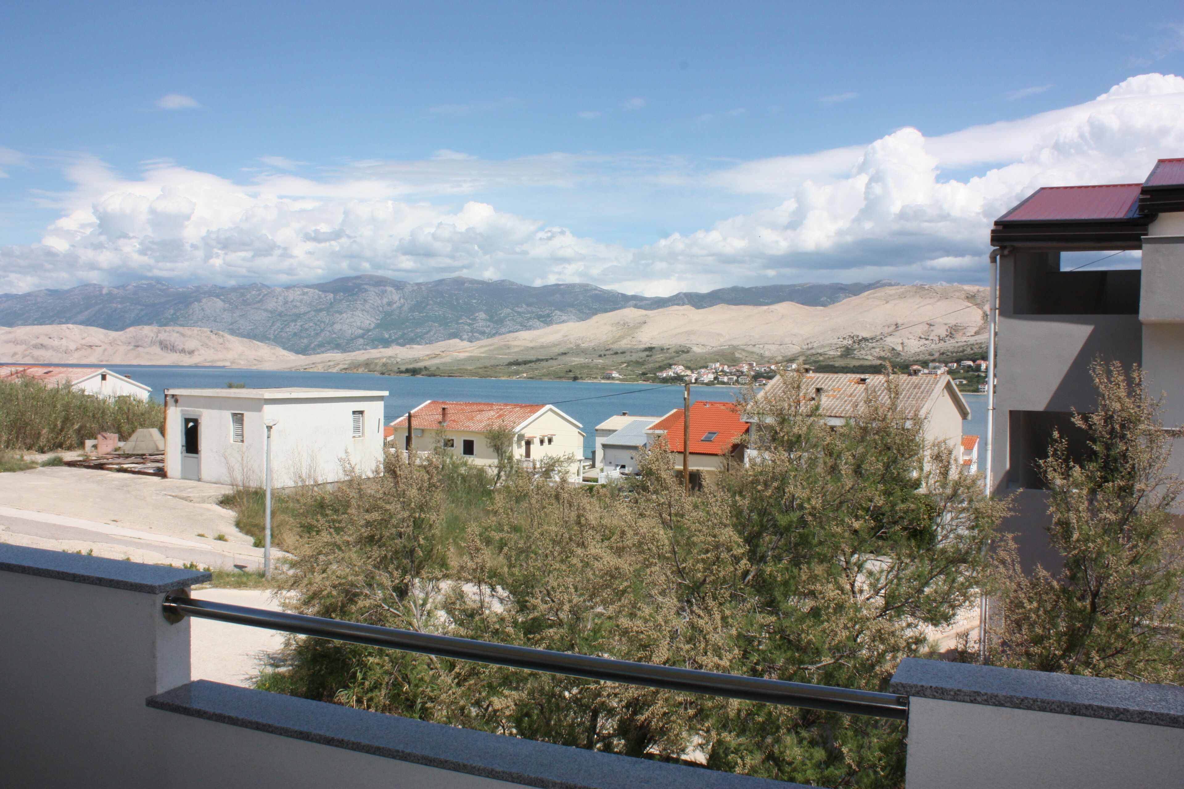 A residential area with houses, a body of water, and mountains in the background.