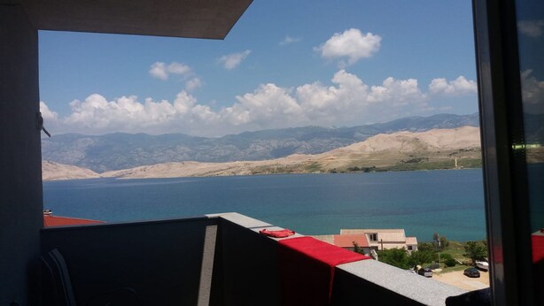 A view from a balcony overlooking a body of water with mountains in the background. - Mare Apartment (Pag)