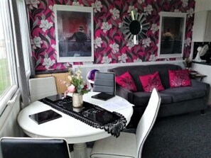 A compact living space with a dining table, chairs, a sofa, and a decorative mirror.