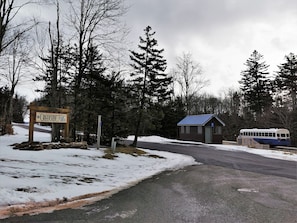 A wooden sign for Creekside Villas, a small building with a blue roof, and a bus parked on the road. - ❤️Great WiFi. Beautiful Home for a Ski Getaway. 15% off of ski rentals  (Snowshoe)