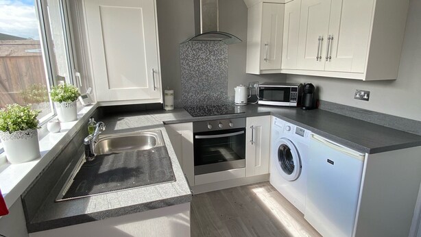 Cocina compacta con lavabo, estufa, horno y microondas. Hay una ventana con vistas al exterior.