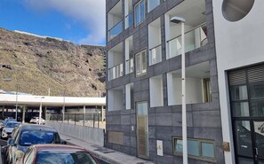 Um edifício moderno com vários andares, grandes janelas e uma área de estacionamento na frente.