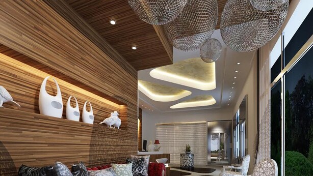A modern living room with a red sofa, decorative wall art, and a unique ceiling design. - Be Inn Hotel (Seeb)