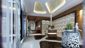 A modern lobby with a reception desk, a large decorative vase, and a unique ceiling design. - Be Inn Hotel (Seeb)
