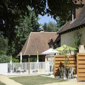 A rustic building with a sloped roof, surrounded by a fenced area with outdoor seating.