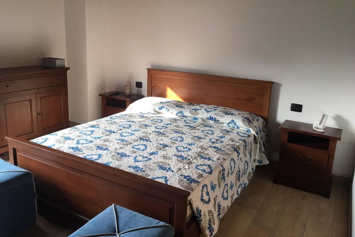 A bedroom with a wooden bed, nightstands, a dresser, and a chair.