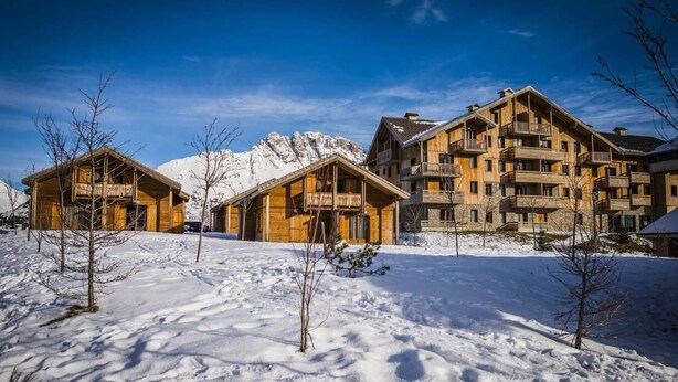 A wooden lodge with multiple balconies and a snow-covered landscape.