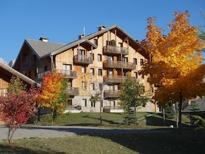Ein mehrstöckiges Holzgebäude mit Balkonen, einem Steinunterbau und blauem Himmel.