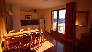 A compact kitchen with a dining area, a small refrigerator, and a microwave.