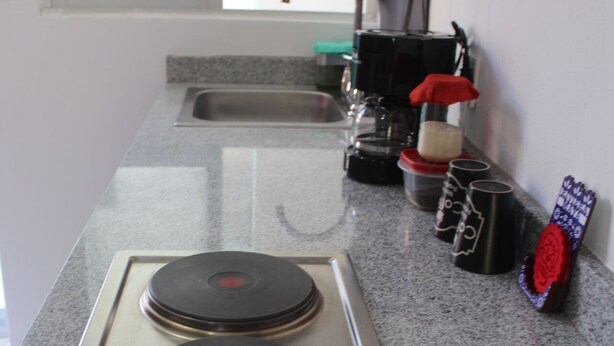 Una cocina con dos placas de inducción, una cafetera y un lavabo.