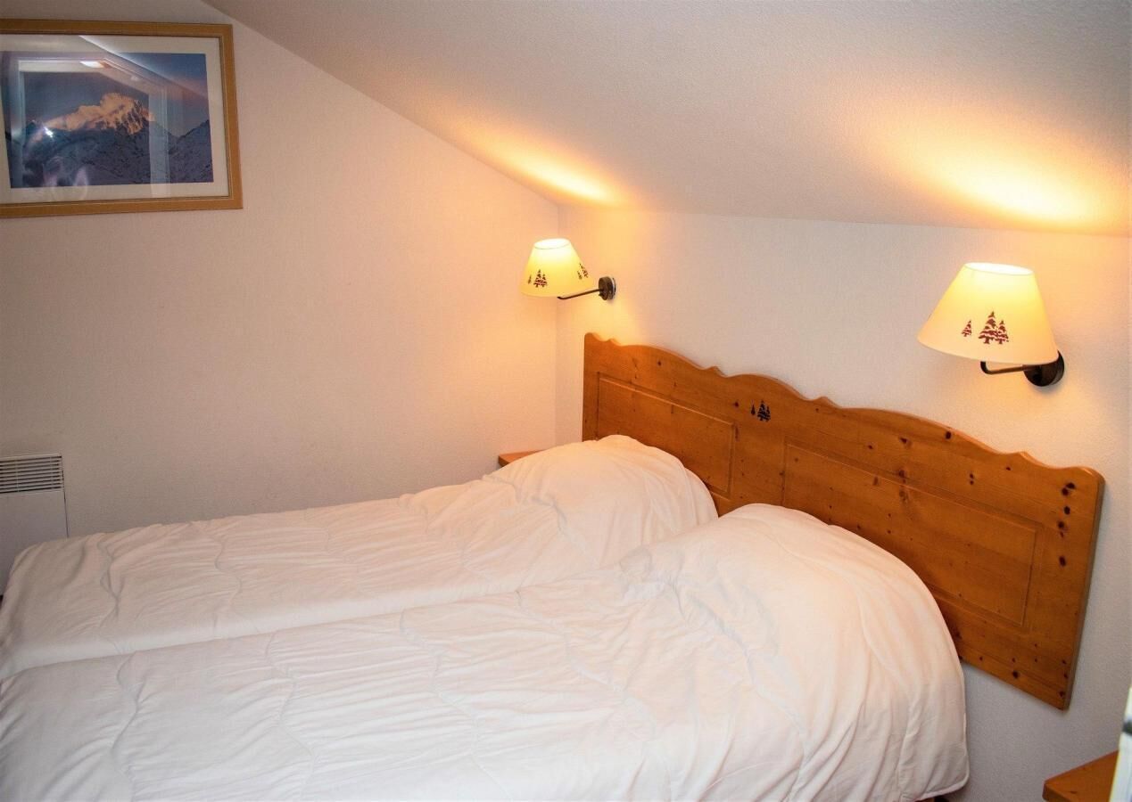 A double bed with a wooden headboard, two wall-mounted lamps, and a framed picture on the wall.