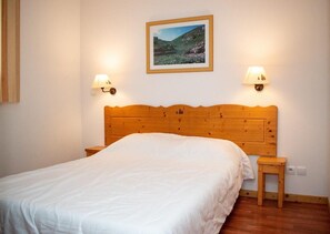 A bedroom with a wooden headboard, a single bed, two bedside lamps, a small bedside table, and a framed picture on the wall. - Chalet, 300m from ski slopes, swimming pool, sauna, terrace, parking, tv, ski locker, 56m² (Le Dévoluy)