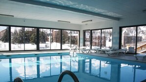 Ein Hallenbad mit freiem Blick auf eine verschneite Landschaft durch große Fenster.